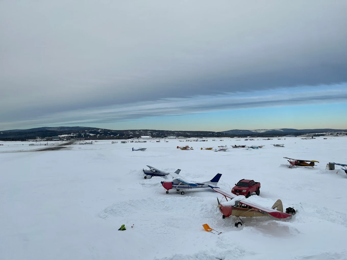 Bush planes half-buried in snow on the Fairbanks East Ramp at a winter dawn